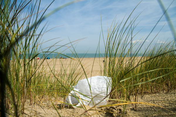 plastic zak op het strand tussen het helmgras